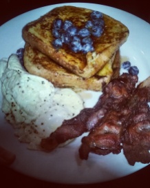 French toast with blueberries and maple syrup, scrambled eggs, bacon